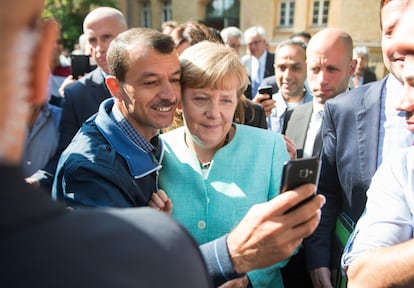 Un inmigrante se hace un selfi con Angela Merkel, durante la visita de la excanciller a la Oficina Federal de Migración y Refugiados en Berlín, en septiembre de 2015.