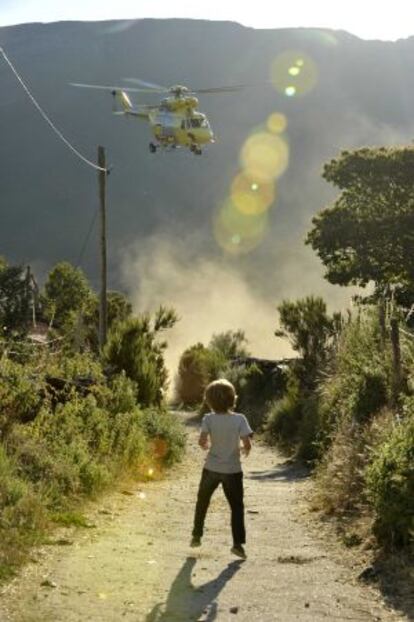 Un niño observa la llegada de un helicóptero para luchar contra el incendio de Chandrexa de Queixa