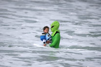 Oliver Quiros, de 3 años, disfrazado de astronauta, junto a su padre, vestido de alienígena, se da un baño durante la celebración del Halloween Surf Contest en Santa Mónica, California (EE UU), el 29 de octubre de 2016.