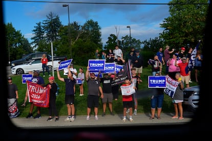 Seguidores de Donald Trump, sostienen carteles mientras la candidata presidencial demócrata, Kamala Harris, pasa en su autobús camino a una parada de campaña  en Pittsburgh, el 18 de agosto de 2024. 