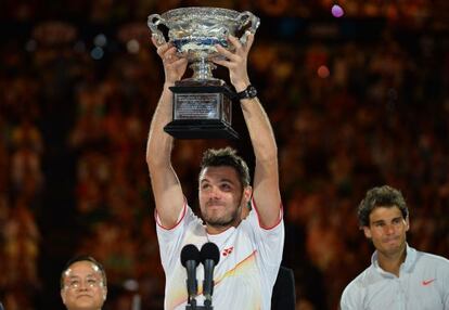 Wawrinka levanta o troféu. Atrás dele, Nadal.