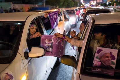 Partidarios de Rohani reparten carteles durante la campaña electoral.