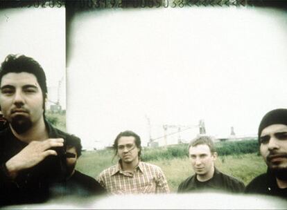 Foto promocional de Deftones, en el centro, con camisa de cuadros, Chi Cheng