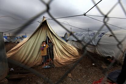 Alaa Ahmed, de ocho años, bebe un té mientras está de pie en la entrada de la tienda de su familia con su hermano, en Dohuk, Irak (2013). El empeoramiento de las condiciones invernales dificultaba la vida diaria de los niños y las familias sirias en el campo de refugiados de Domiz, en el norte de Irak. Según ACNUR, más de 40.000 refugiados sirios estaban registrados en este campamento, el doble de la cantidad para la que fue creado.