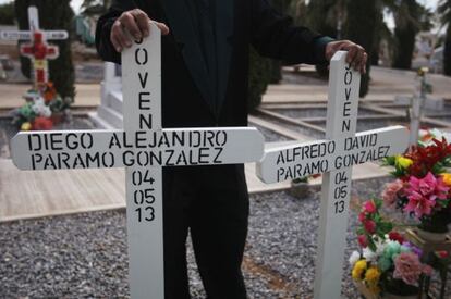 A funeral worker holds the crosses for the graves of two young men shot dead in Chihuahua on Saturday.