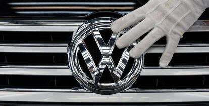 Una imagen de un empleado de Volkswagen tocando el logotipo de la marca