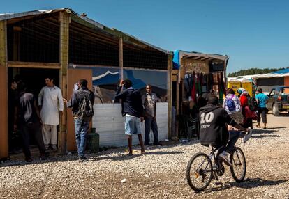 Migrantes caminan frente a una tienda improvisada en 'La Jungla' de Calais. La Delegación del Gobierno había solicitado el cierre administrativo de esas tiendas, bares y restaurantes, donde miles de migrantes esperan para poder cruzar a Gran Bretaña.