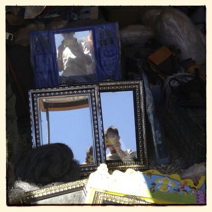 Omar, de 14 años, se autoretrata en los espejos de una tienda en la calle central del campamento.