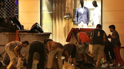 Un grupo de personas busca comida en la basura de un centro comercial del centro de Madrid.