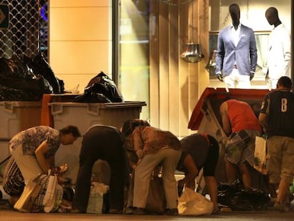 Un grupo de personas busca comida en la basura de un centro comercial del centro de Madrid.