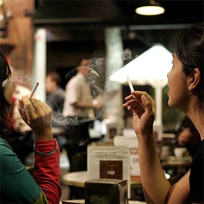 Dos mujeres fuman en una cafetería.