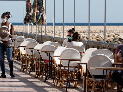 Una camarera atiende a dos clientas en una terraza en la localidad Alicantina de Denia, uno de los territorios de España que comienza la Fase 1.