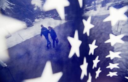 Una pareja que se dirige a su lugar de votación durante las primarias de New Hampshire, vista a través de una bandera de Estados Unidos.