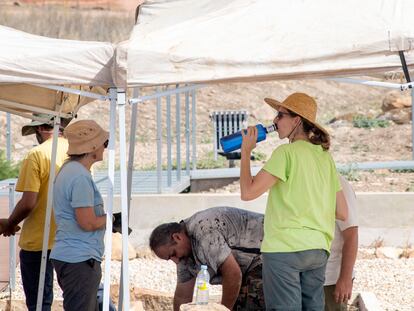 Un grupo de arqueólogos se protegen a mediodía del sol en Jaén, con sombreros, toldos para el trabajo y agua.