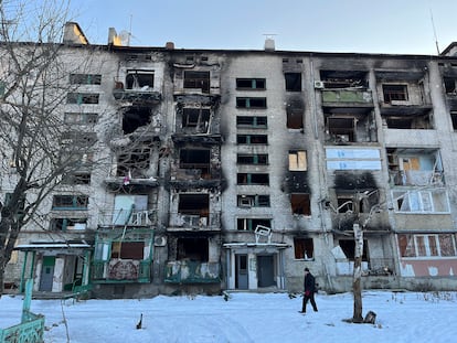 Un vecino de Limán, en la provincia de Donetsk, camina sobre la nieve ante un edificio bombardeado.