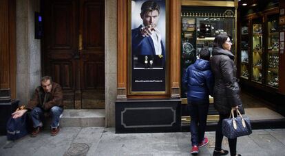 Un mendigo pide limosna al lado de una joyería, en Madrid en 2016.