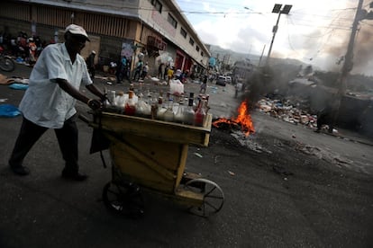 Um homem empurra uma carroça com bebidas enquanto passa por uma barricada em chamas durante os protestos de 17 de fevereiro.