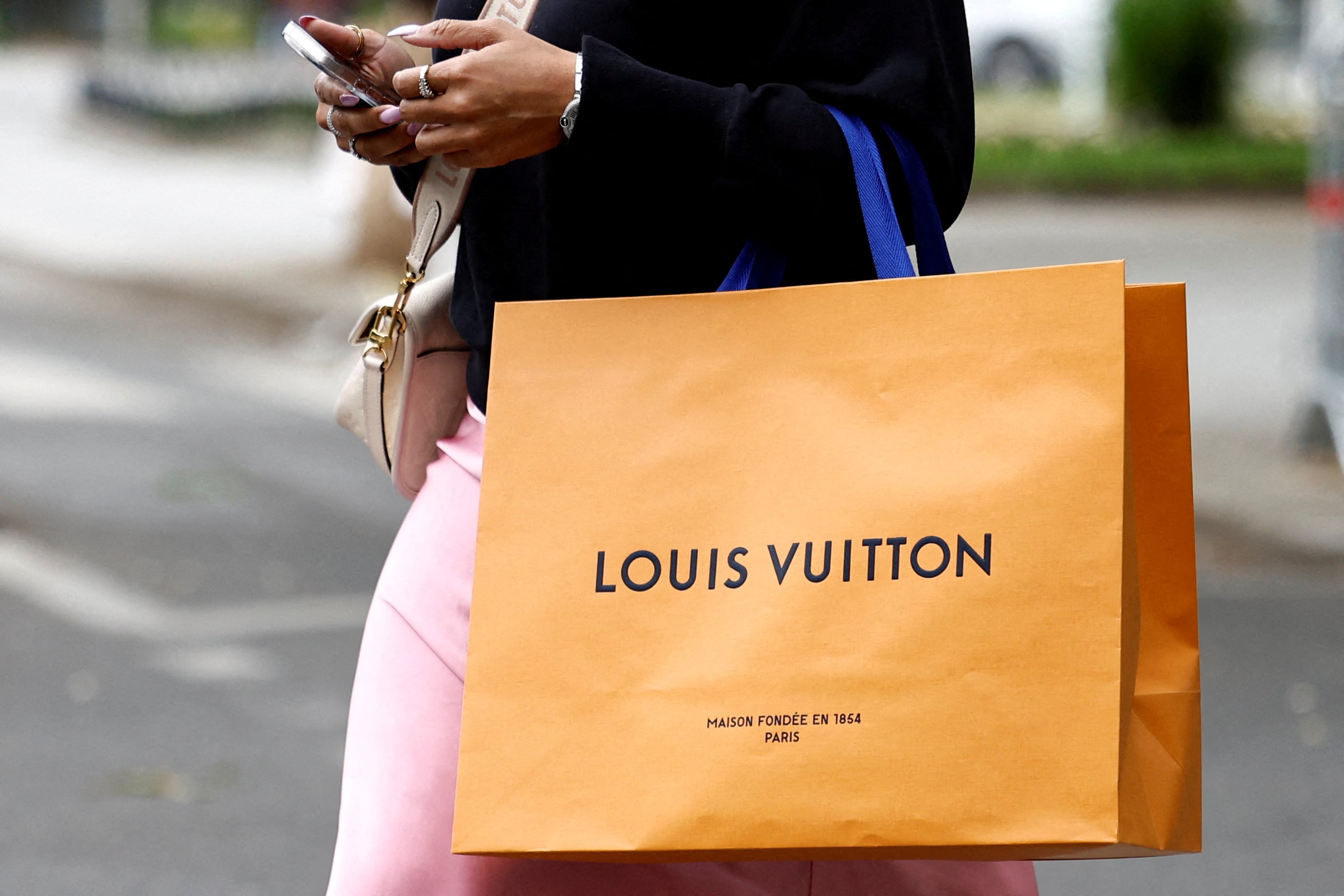 Una mujer pasea con una bolsa de Louis Vuitton en París, Francia, el pasado mes de abril.