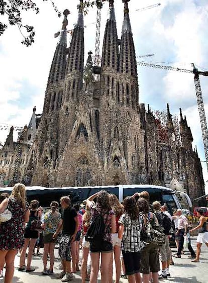 Turistas después de bajar de un autocar frente a la fachada del Nacimiento de la Sagrada Família.