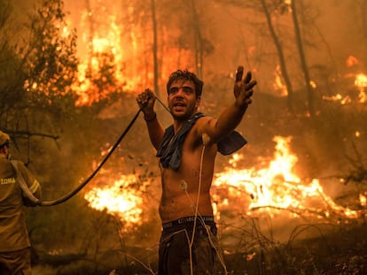 Un residente local hace un gesto mientras sostiene una manguera de agua vacía durante un intento de extinguir los incendios forestales que se acercan al pueblo de Pefki en la isla de Evia (Eubea), Grecia.