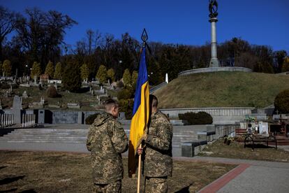 Un soldado ucranio porta la bandera de su país mientras habla con un compañero durante el funeral por el sargento Kostiantyn Deriuhin, muerto en la ofensiva rusa, el domingo en el cementerio de Lychakiv, en Lviv.
