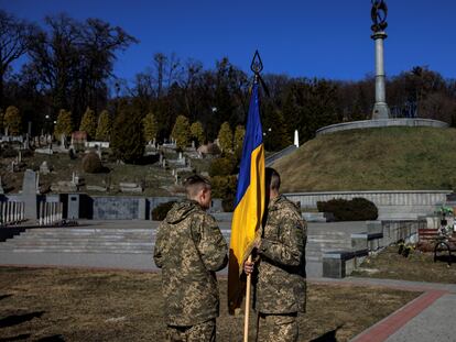 Un soldado ucranio porta la bandera de su país mientras habla con un compañero durante el funeral por el sargento Kostiantyn Deriuhin, muerto en la ofensiva rusa, el domingo en el cementerio de Lychakiv, en Lviv.