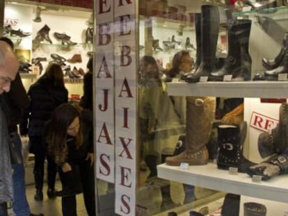 Un hombre mira los precios en el escaparate de una tienda.