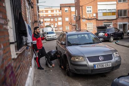 Dos hombres improvisan un taller de coches en una calle de Las Viudas.
