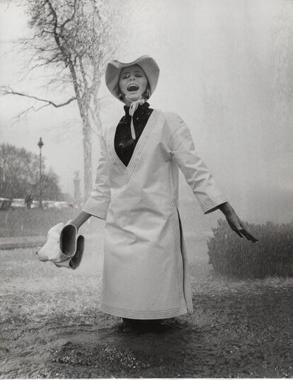 Jill Kennington viste impermeable y gorro de lluvia de PVC blanco.
