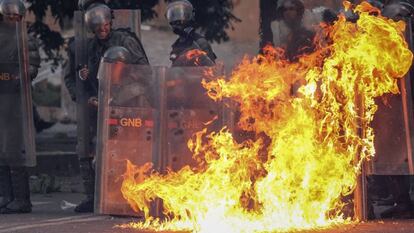 Miembros de la Guardia Nacional Bolivariana (GNB) se protegen del fuego en medio de las protestas en Caracas, en junio de 2017.