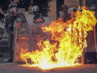 Miembros de la Guardia Nacional Bolivariana (GNB) se protegen del fuego en medio de las protestas en Caracas, en junio de 2017.