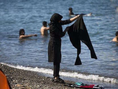 Una mujer inmigrante lava la ropa en presencia de varios bañistas, ayer en una playa de Kos en Grecia.