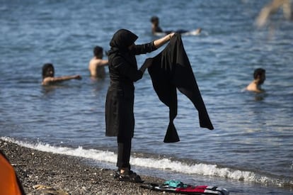 Una mujer inmigrante lava la ropa en presencia de varios bañistas, ayer en una playa de Kos en Grecia.