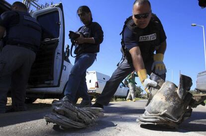 Un zapador de polic&iacute;a israel&iacute; recoge los restos de un cohete ca&iacute;do junto a una carretera de Askel&oacute;n, al sur de Israel.