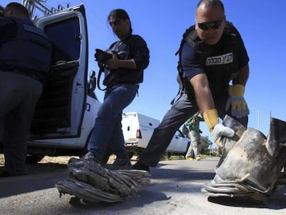 Un zapador de polic&iacute;a israel&iacute; recoge los restos de un cohete ca&iacute;do junto a una carretera de Askel&oacute;n, al sur de Israel.