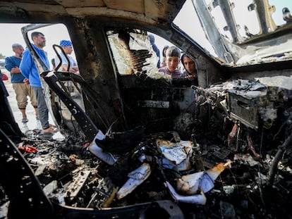 Varias personas inspeccionan uno de los coches donde viajaban los trabajadores que han muerto durante un ataque israelí, este martes en el sur de Gaza.