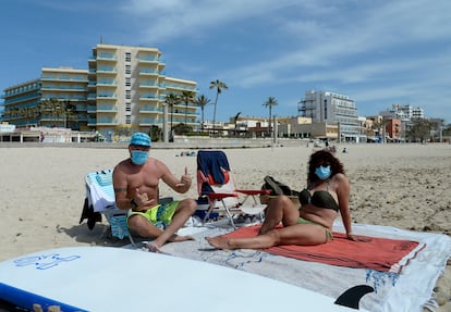 Beachgoers wearing face masks on a beach in Mallorca in Spain‘s Balearic Islands.