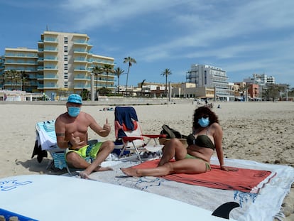 Beachgoers wearing face masks on a beach in Mallorca in Spain‘s Balearic Islands.