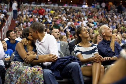 Barack Obama y su esposa se besan en un momento del partido entre la selección de baloncesto de Estados Unidos y Brasil en el estadio Verizon Center, en Washington DC, junto al vicepresidente Joe Biden, el 16 de julio de 2012.
