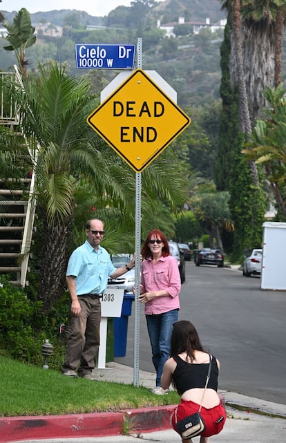 Two tourists have their picture taken next to the Cielo Drive road sign.