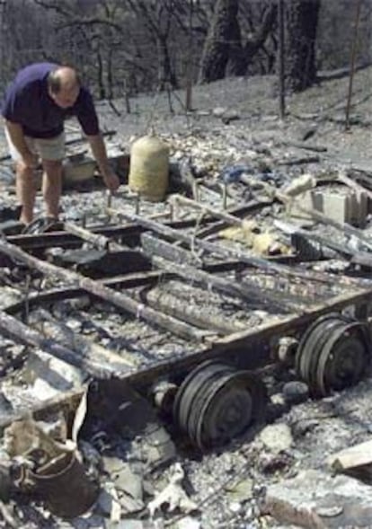 Un hombre observa los restos carbonizados de su vehículo.