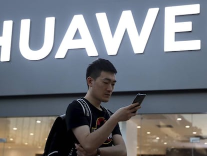 Un hombre usando su smartphone delante de una tienda de Huawei en Beijing.