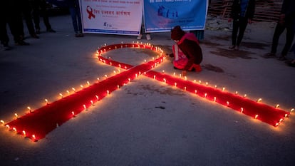 Mulheres e crianças do orfanato de recuperação para pacientes de Aids Maiti Nepal, acendem velas formando um laço vermelho, em Katmandu.