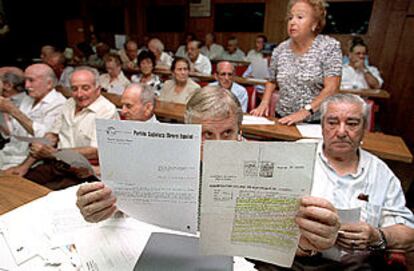 Asistentes a la asamblea muestran documentos sobre su condición de ex presos políticos.