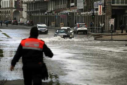  Varios vehículos circulan por una calle de A Coruña que se encuentra inundada tras sobrepasar las olas el paseo marítimo de la ciudad.