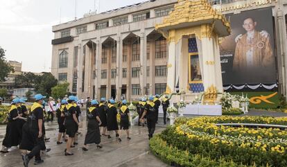 Voluntarios tailandedes van a poner flores en frente de un retrato gigante del fallecido rey Bhumibol este jueves. 