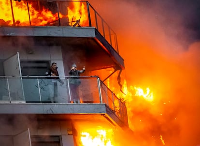 Dos vecinos piden ayuda desde el balcón de un edificio que está siendo devorado por las llamas en el barrio valenciano de Campanar, el 22 de febrero. 