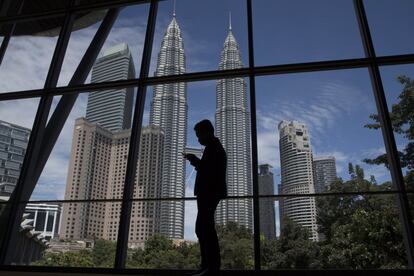 Silueta de un trabajador frente a las Torres Petronas durante la Cumbre de la Asociación de Naciones del Sudeste Asiático en el Centro de Convenciones de Kuala Lumpur (Malasia).