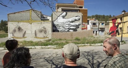 Integrantes del colectivo MIAU contemplan algunas obras pintadas en las fachadas de Fanzara.