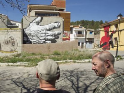 Integrantes del colectivo MIAU contemplan algunas obras pintadas en las fachadas de Fanzara, en una imagen de archivo.